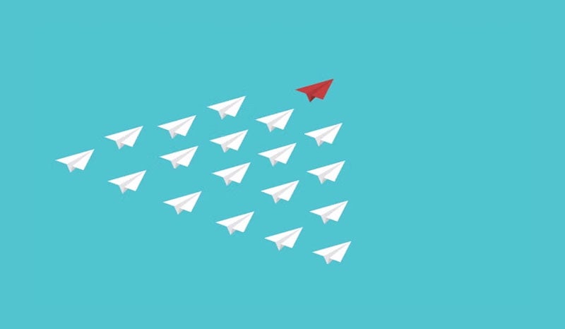 An illustration of paper airplanes with one red airplane leading the others.