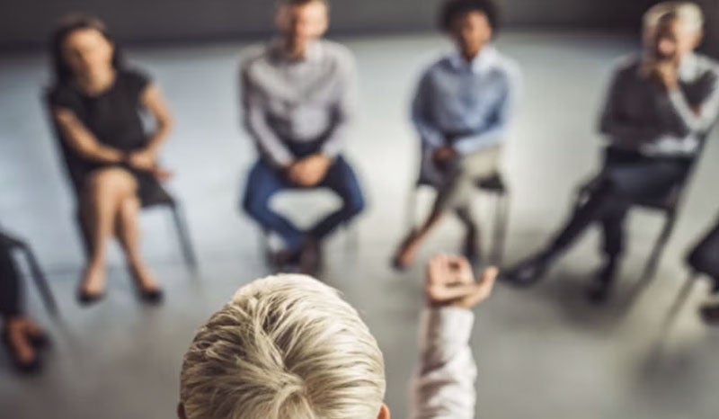 A person presenting to a group of colleagues during a meeting in a modern office.