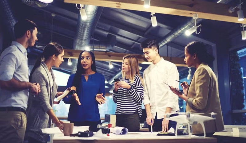A diverse team engaged in discussion in a creative workspace.