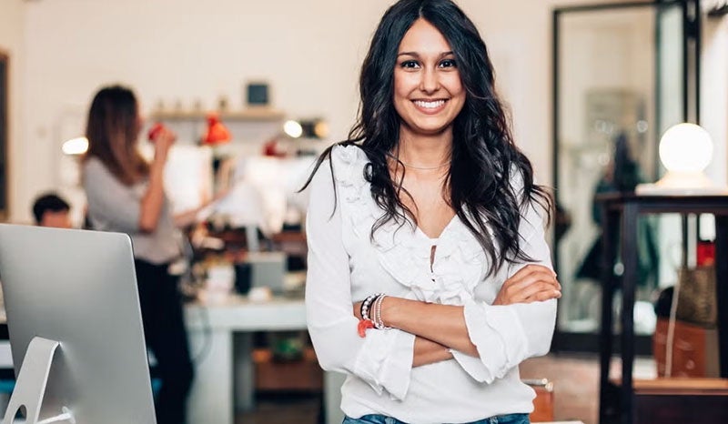 A young woman smiling confidently while standing in an office.